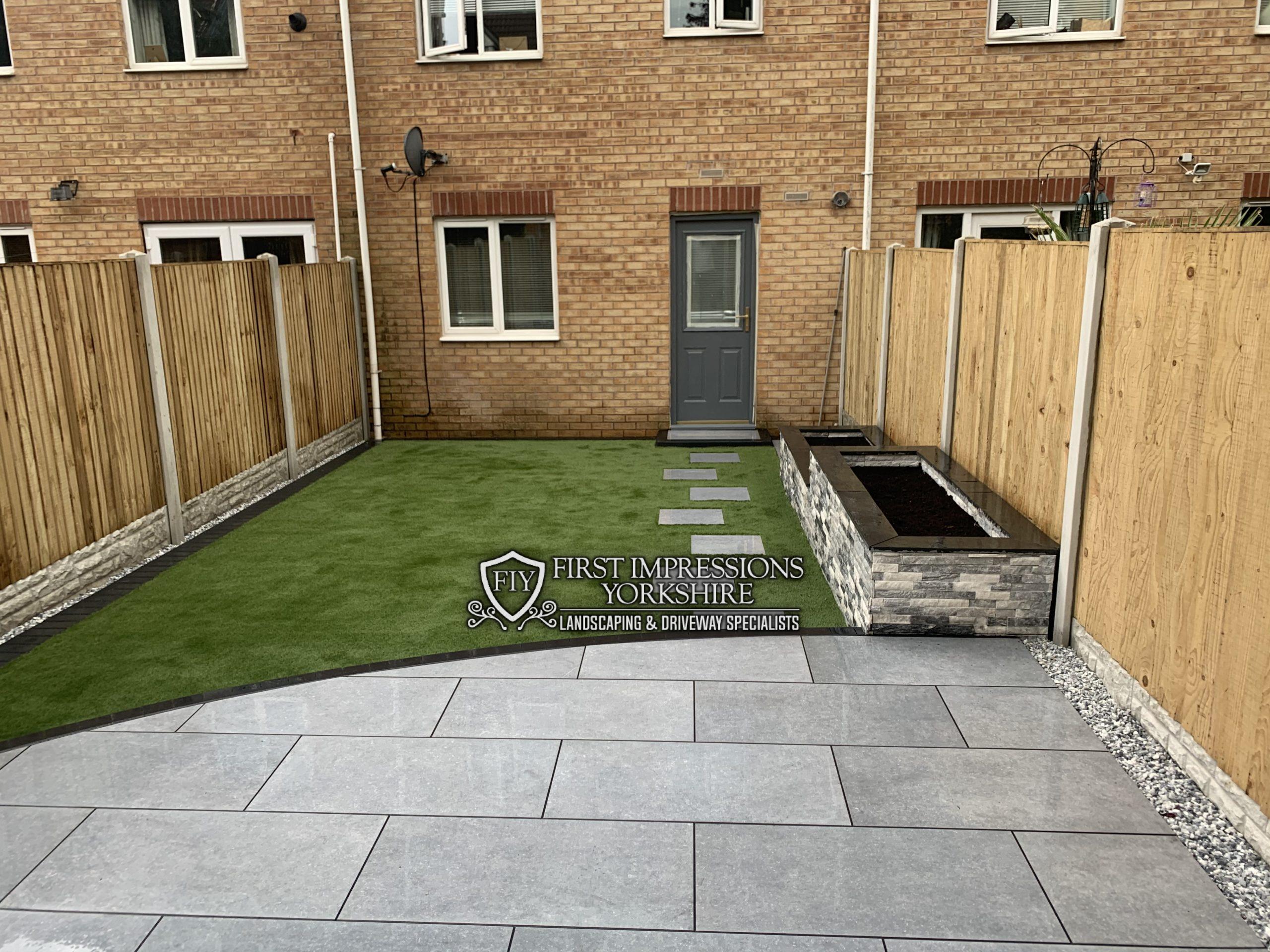 Landscaped rear garden with lawn, porcelain paving and a raised stone planter