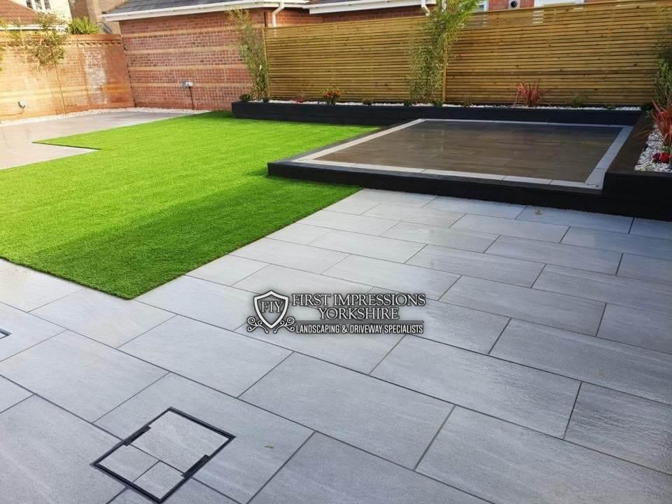 Grey porcelain patio with lawn and raised beds