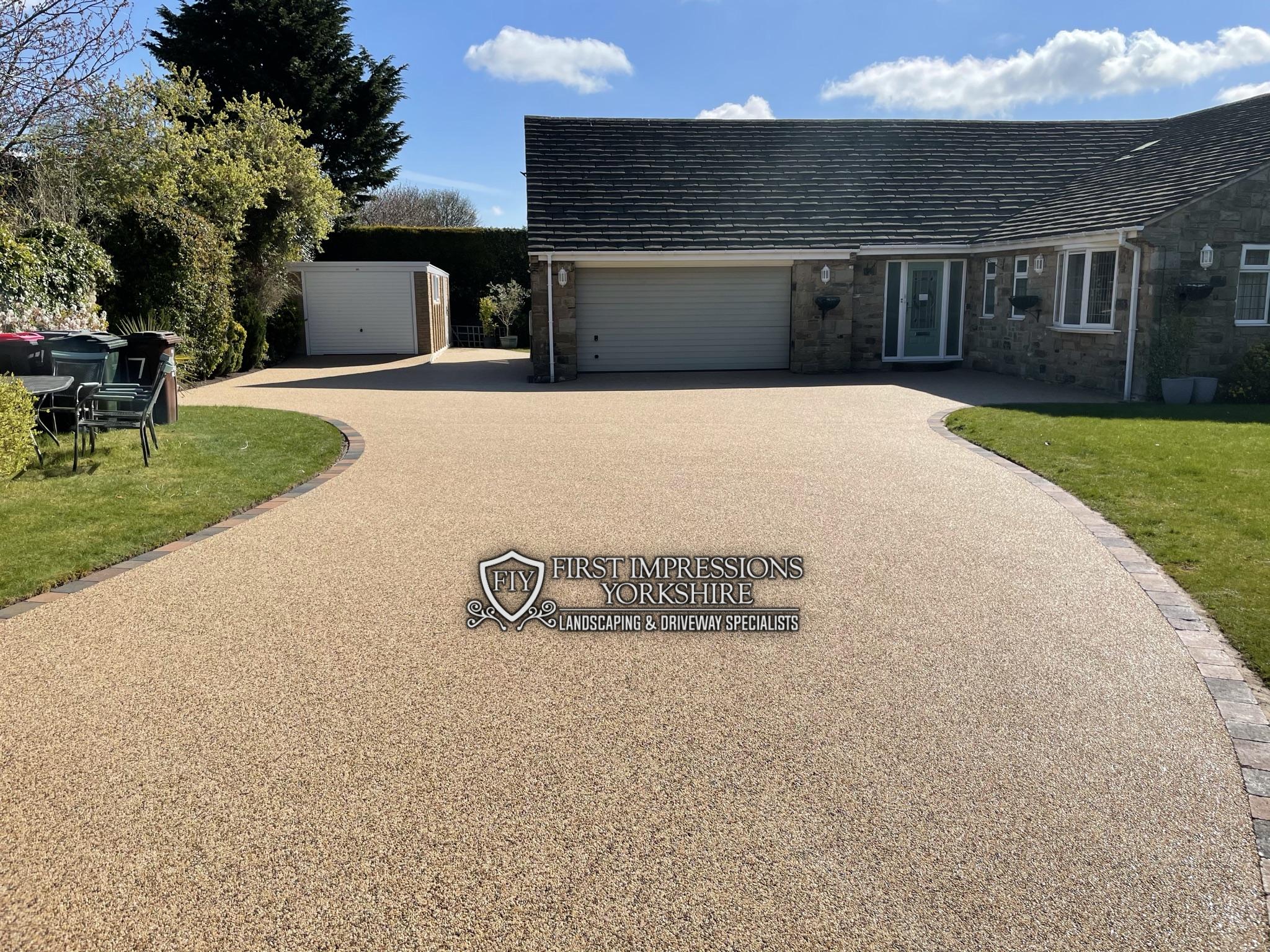 Gold resin bound driveway laid to a bungalow with a block paved border