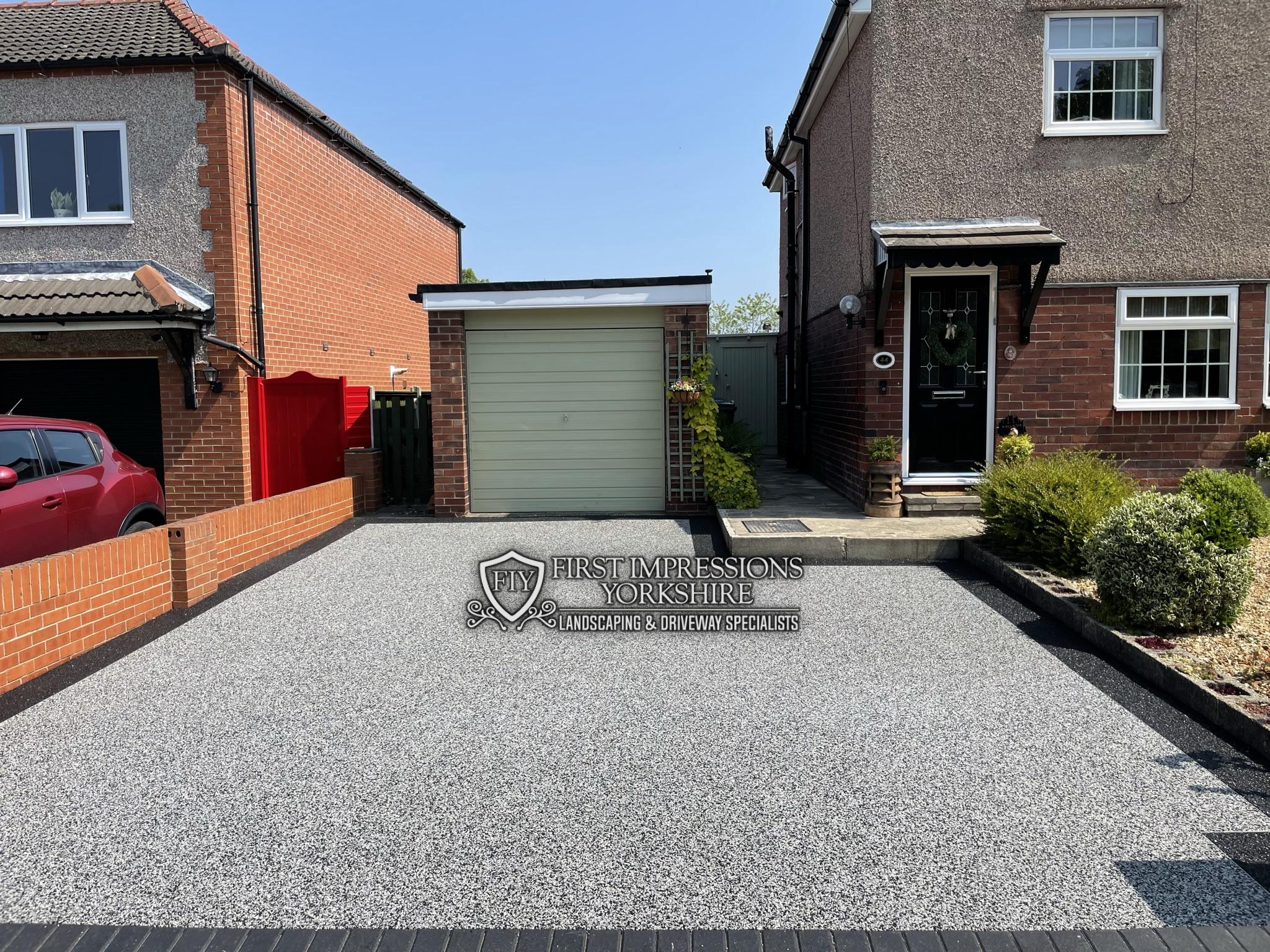 Pewter resin bound driveway with a black block paved apron at the road
