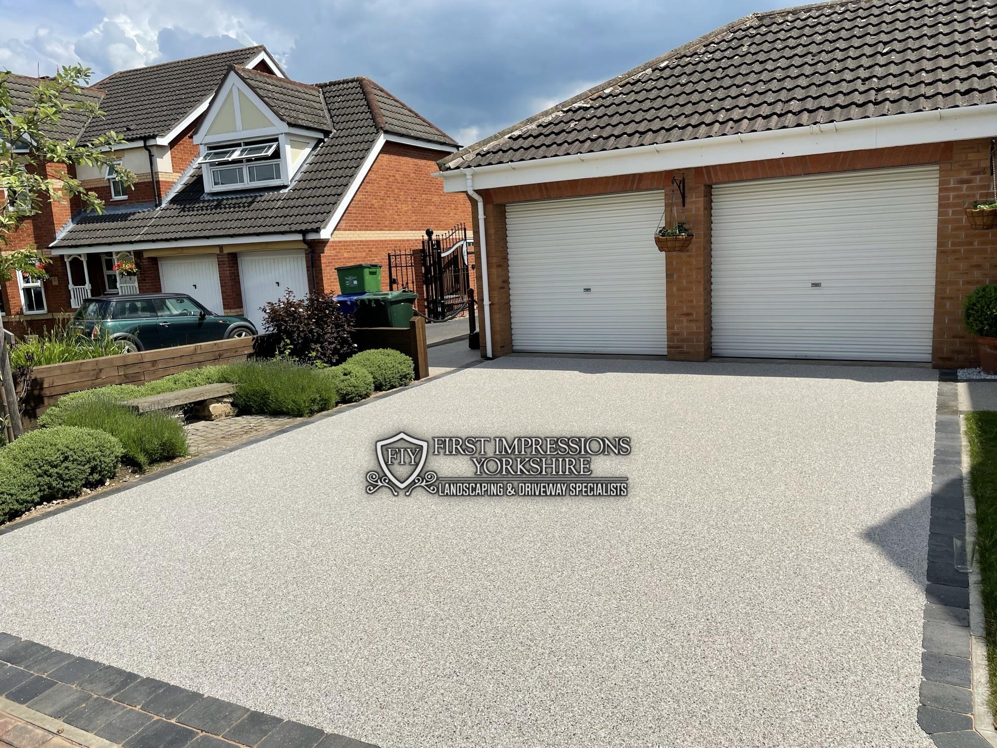 Wide resin bound driveway to a double garage with lavender planting alongside